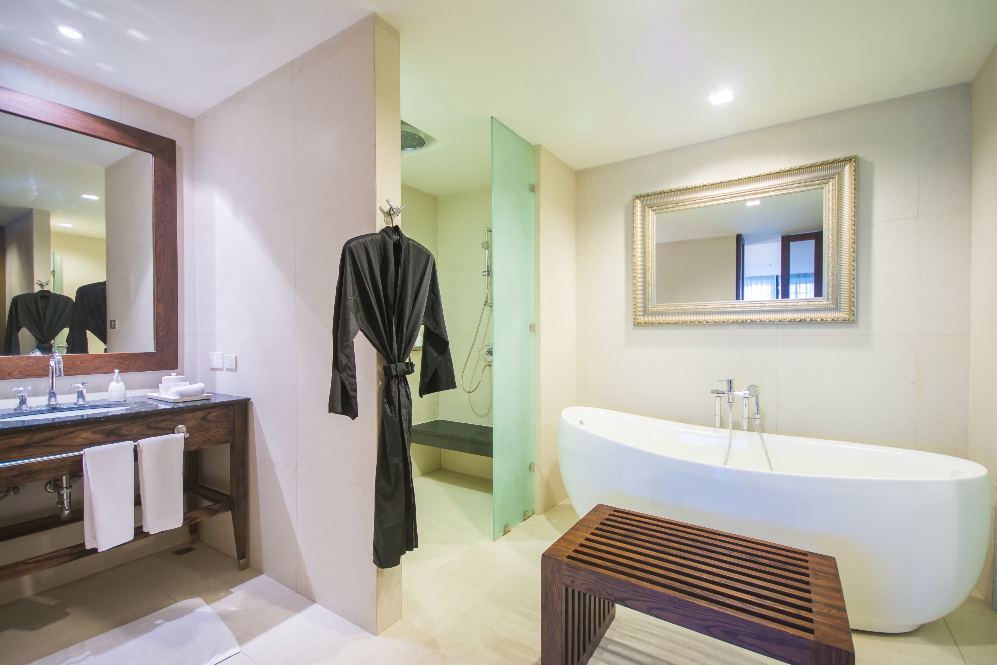Un baño moderno con una bañera independiente, un tocador con espejo y una bata colgada en un perchero.