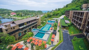 A resort with multiple swimming pools, a large building with balconies, and a view of a lake and mountains. - SUNSURI PHUKET, Nai Harn Beach (Rawai)