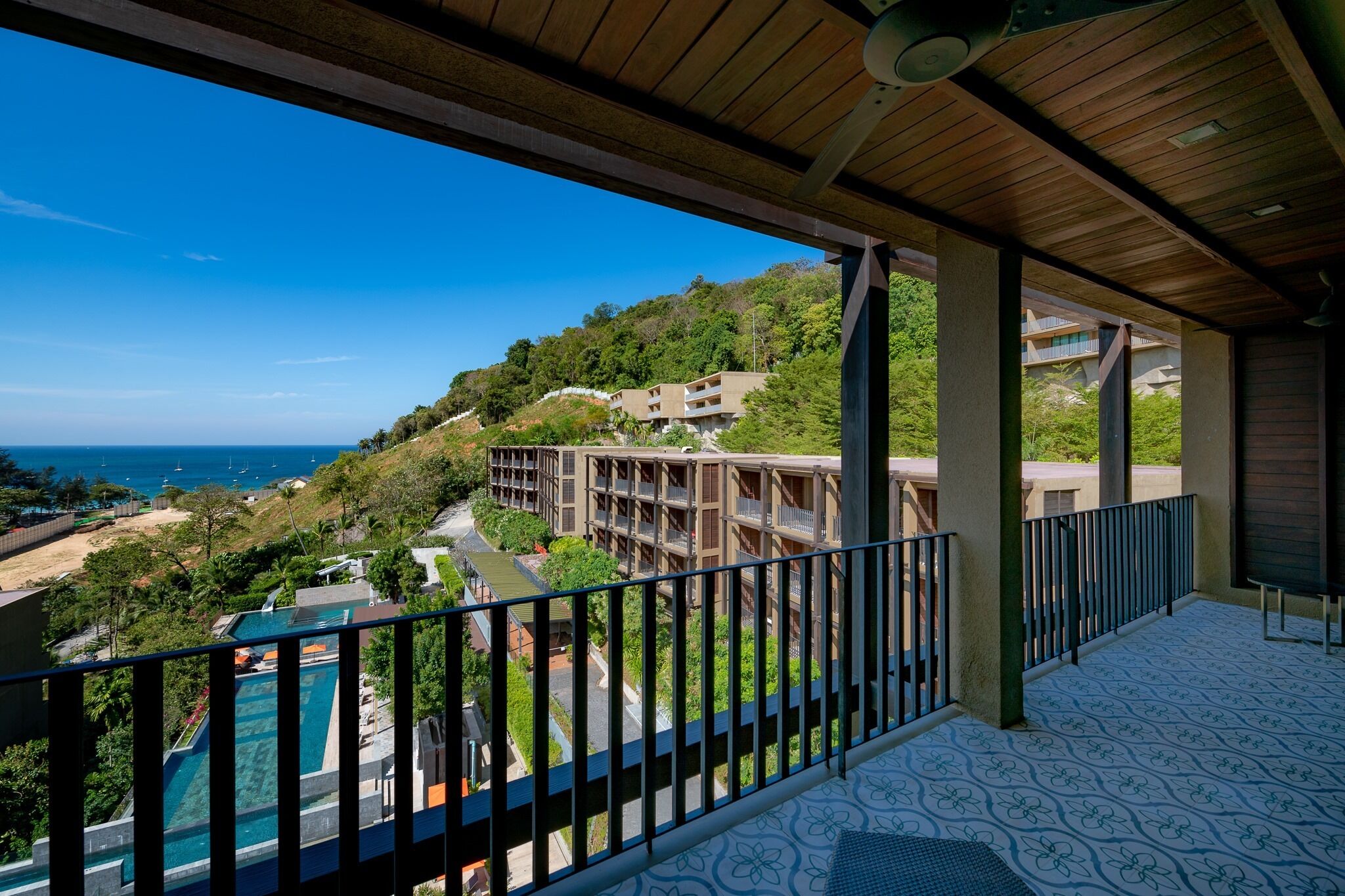 Un balcon avec vue sur une piscine, une plage et des bâtiments situés sur une colline.