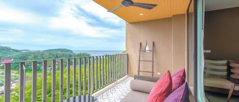A balcony with a table and chairs, a ceiling fan, and a view of a green landscape.