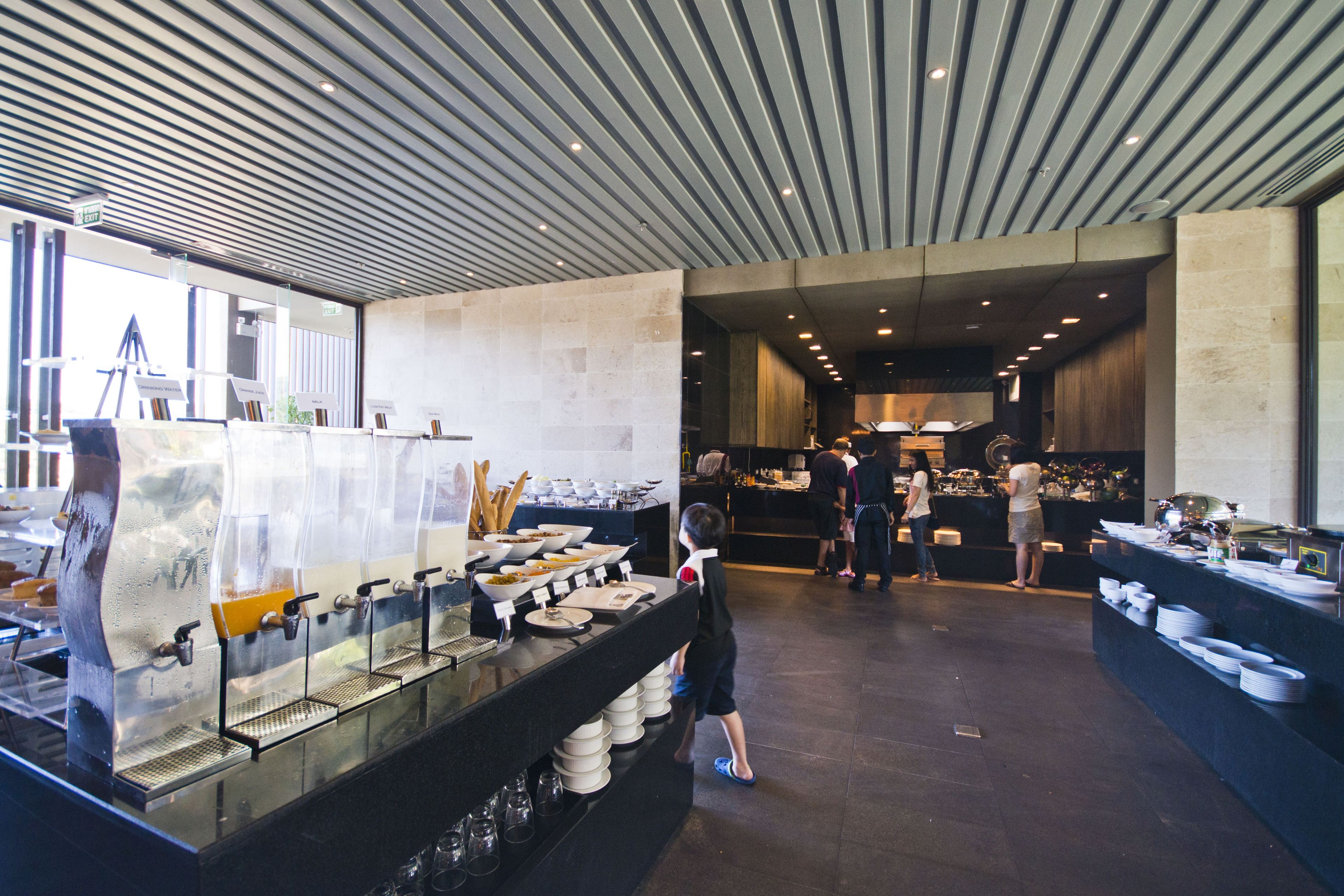 A buffet area with multiple food stations, a child, and adults in the background.