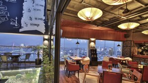 A restaurant with a view of the cityscape, wooden flooring, and modern pendant lighting. - Brilliant Hotel (Da Nang)