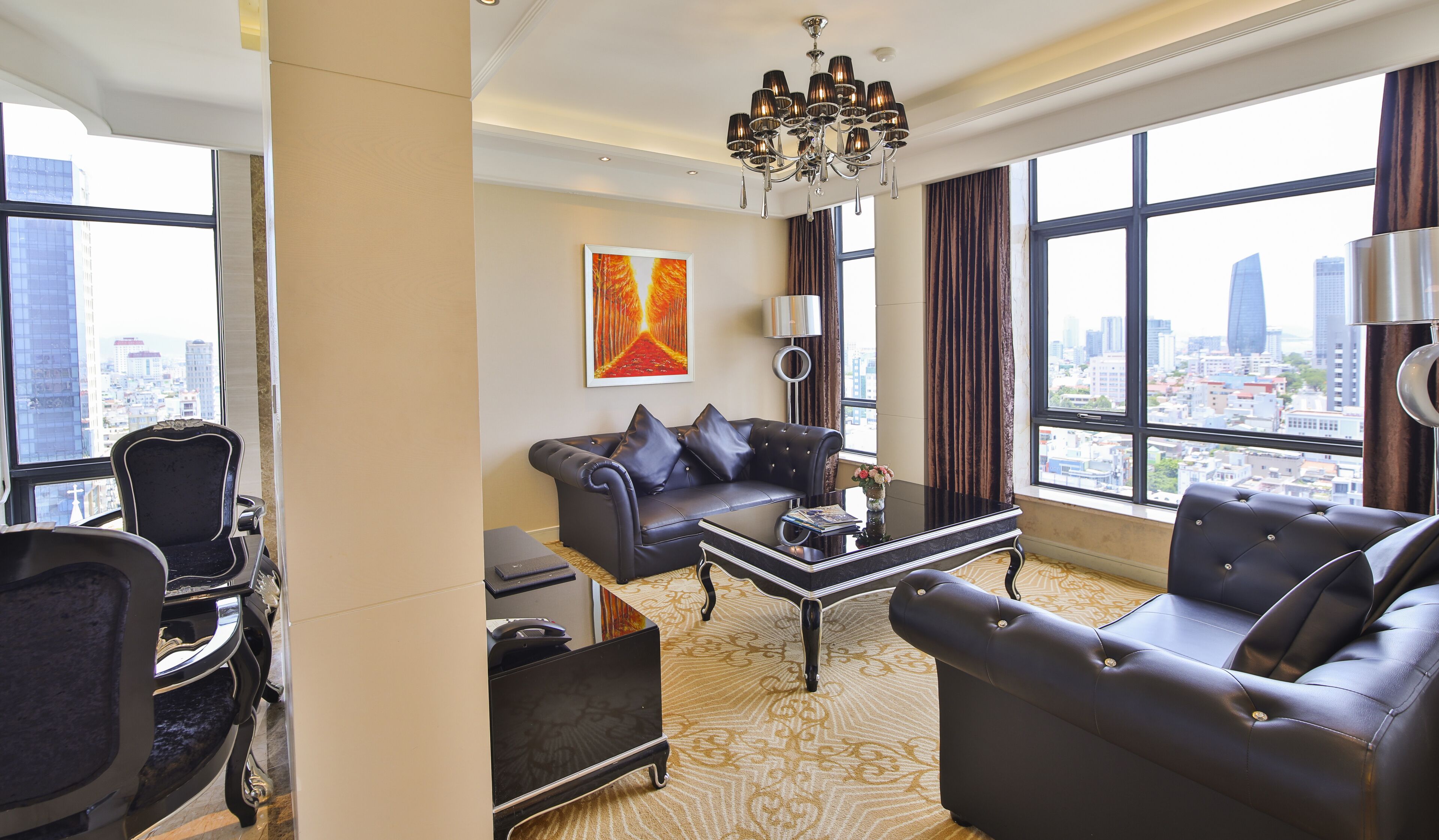 Una sala de estar moderna con un sofá, sillones y una mesa de centro. Se aprecia un ventanal con vistas a la ciudad.