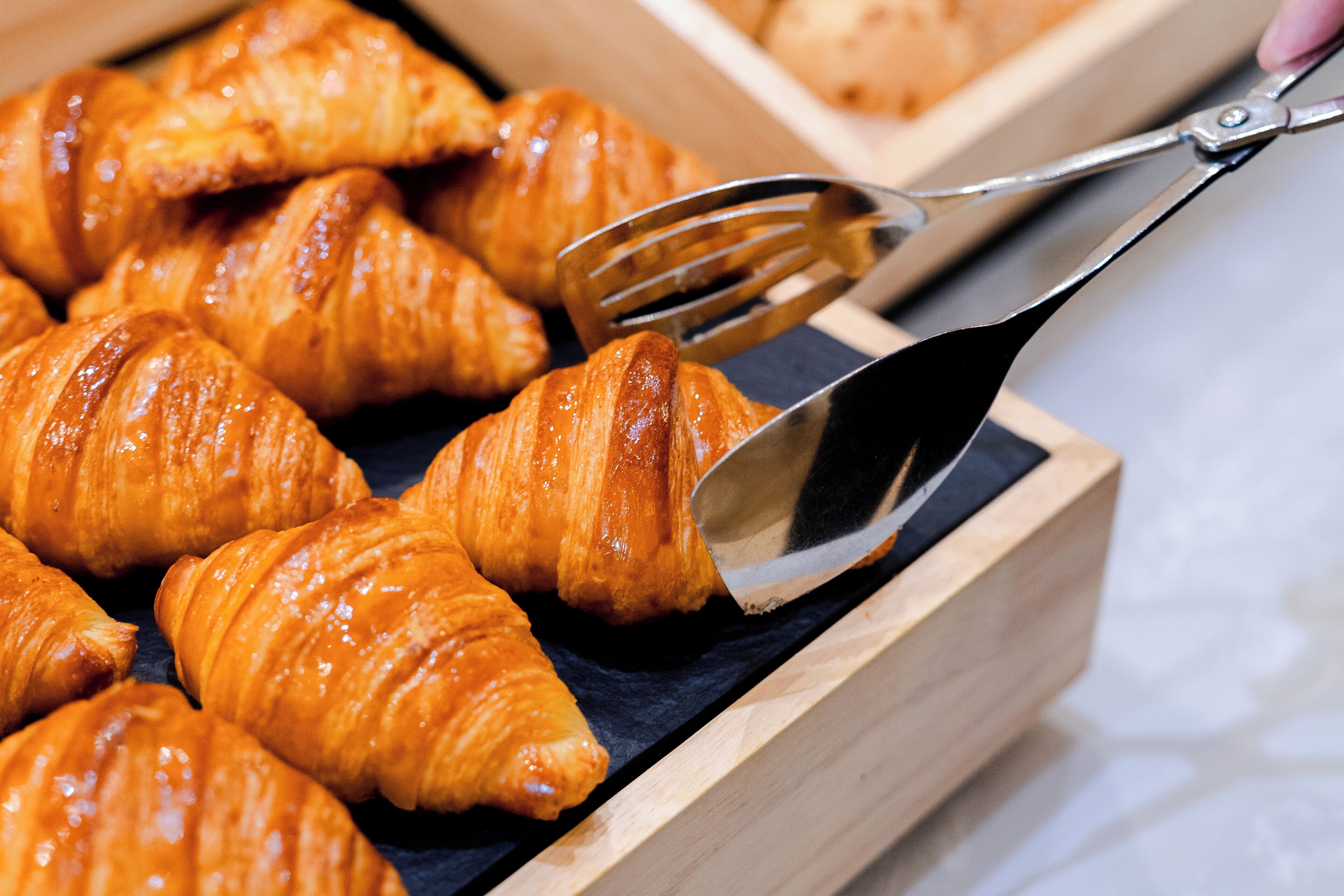 A wooden box filled with golden-brown croissants.