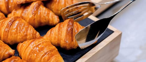 A wooden box filled with golden-brown croissants.