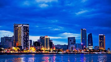 Un horizonte urbano con edificios iluminados y un cuerpo de agua que refleja las luces.