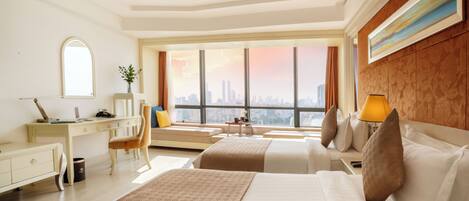 Habitación de hotel con una cama grande, un escritorio, una silla y vistas a un horizonte urbano.