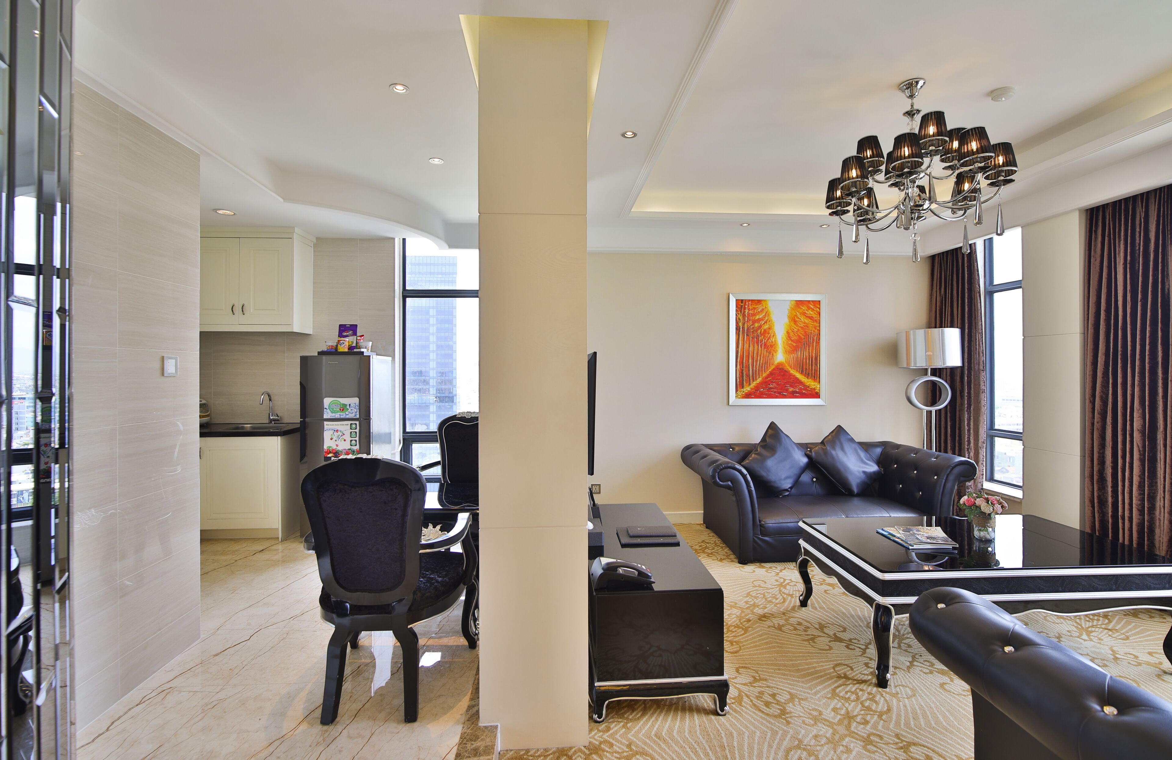 A modern living room with a black sofa, a coffee table, and a dining area with a chair and a small table.