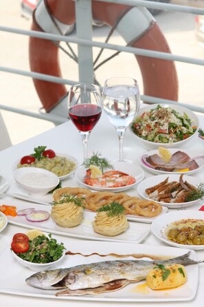 Mesa posta com diversos pratos, incluindo frutos do mar, saladas e bebidas.