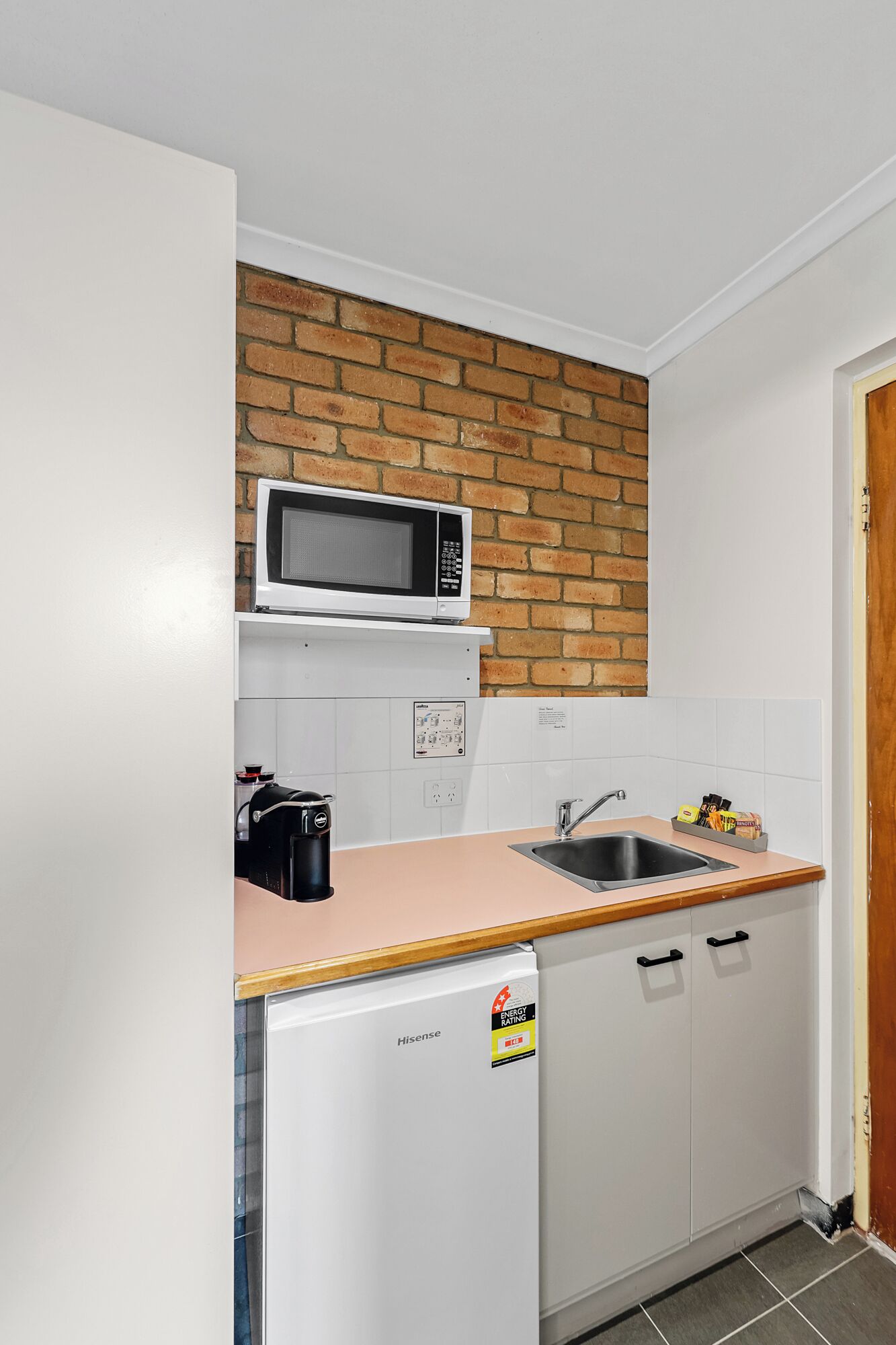 A compact kitchen with a microwave, sink, and a Hisense refrigerator.