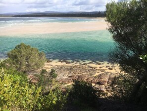 A coastal landscape with clear waters, sandy beach, and rocky outcrops. - Sapphire Waters Motor Inn (Merimbula)