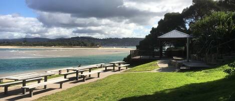 Un parc situé au bord de la plage, équipé de tables de pique-nique et d’un kiosque offrant une vue sur l’océan.