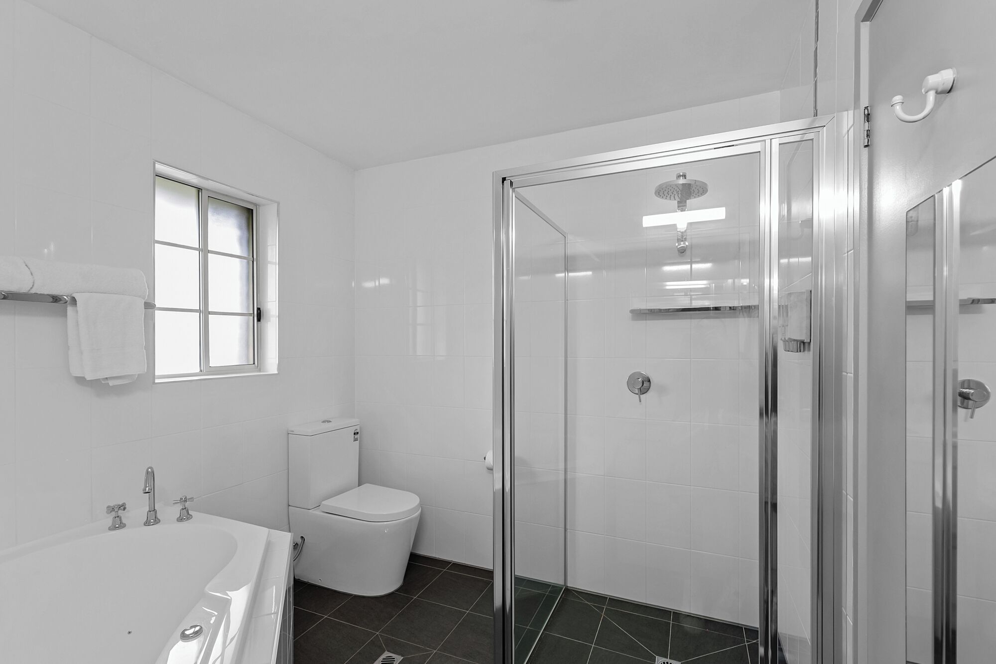 A modern bathroom with a glass-enclosed shower, a white toilet, and a bathtub.