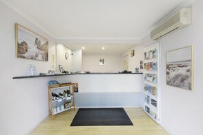 A reception area with a reception desk, a water dispenser, a wine cooler, and a wall-mounted air conditioner.