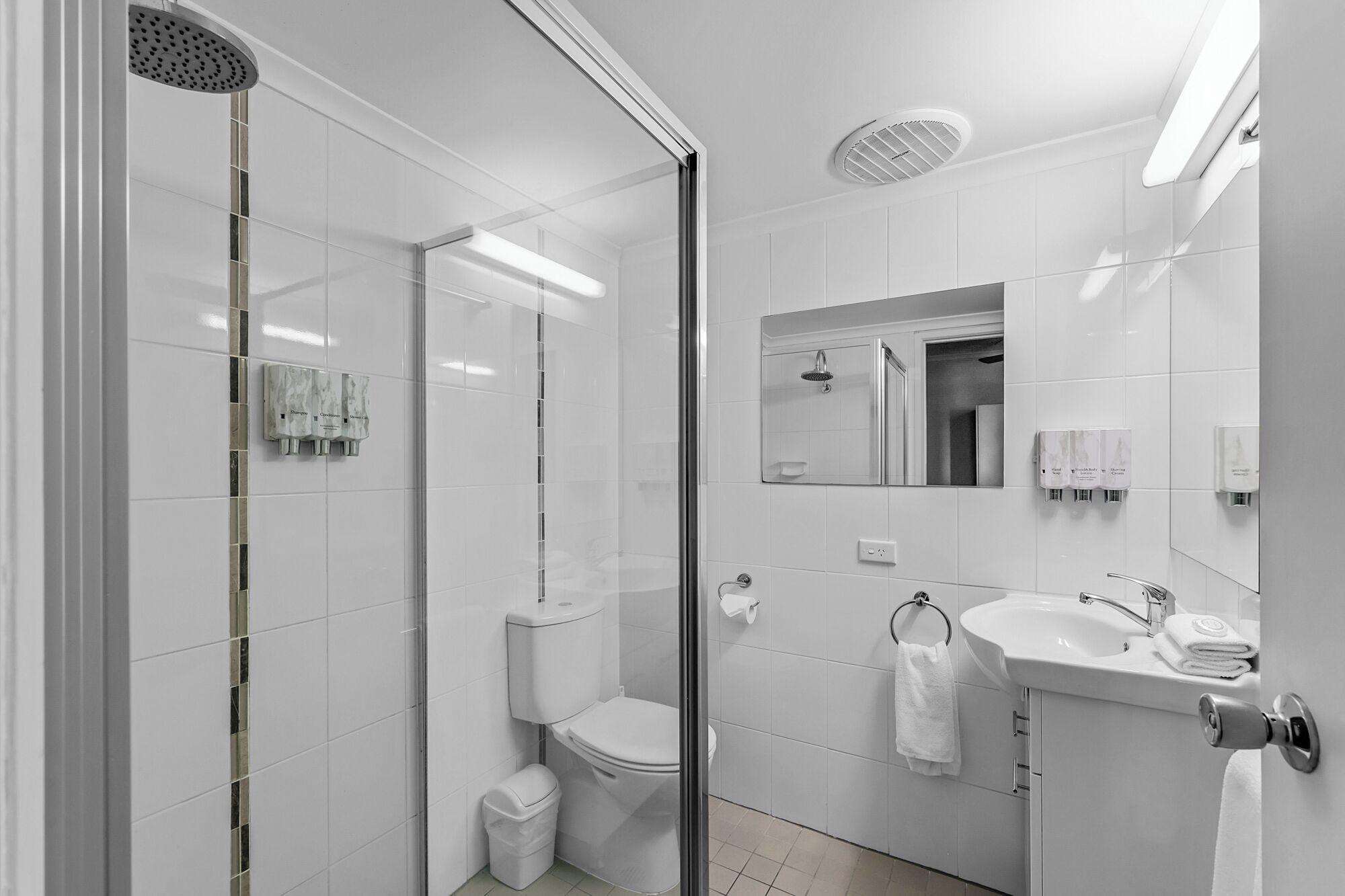 Une salle de bain moderne avec une douche à parois de verre, des toilettes, un lavabo et un miroir.