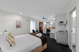 Una habitación de hotel con cama, escritorio, kitchenette y baño.