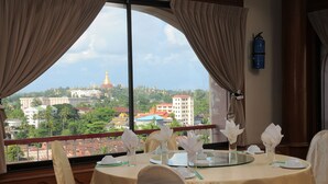 Mesa de comedor con servilletas blancas y cristalería, con vistas a un paisaje urbano que incluye edificios destacados y una estructura de cúpula dorada.