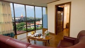 Una habitación con un ventanal grande, una mesa de madera con alimentos para el desayuno, un sofá y vistas a un edificio de cúpula dorada.