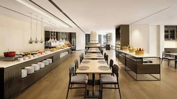 A modern dining area with long tables, chairs, and a buffet setup.