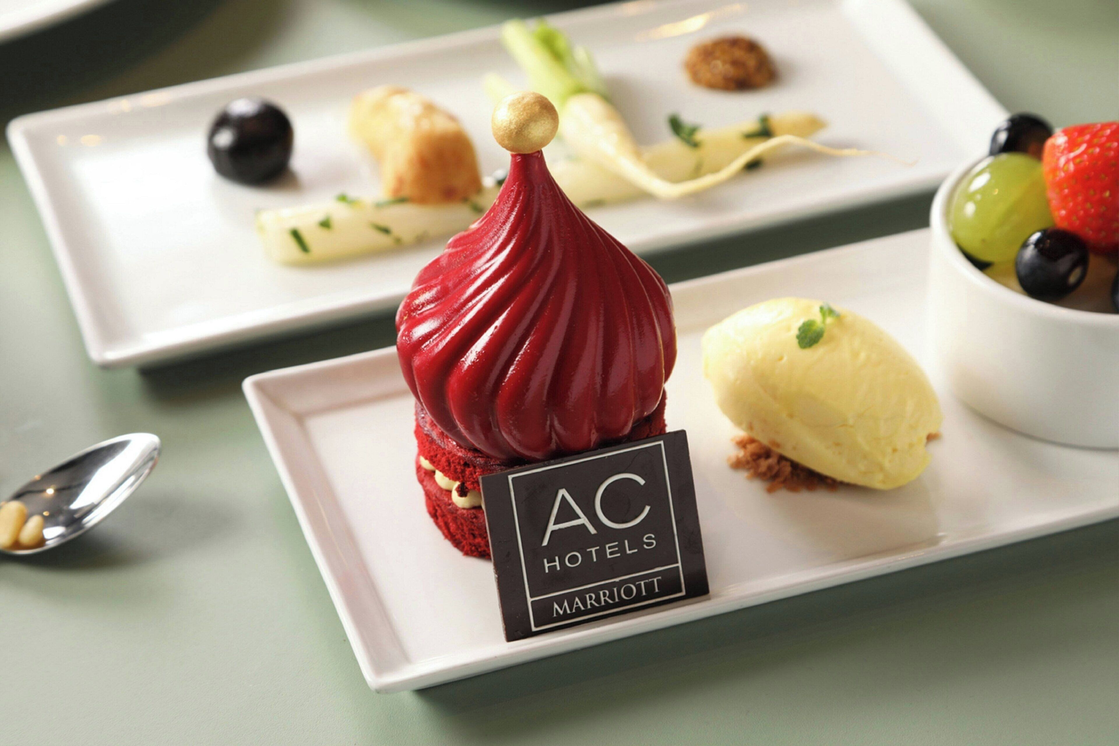 A dessert plate with a red sauce and a sign that reads "AC Hotels Marriott".