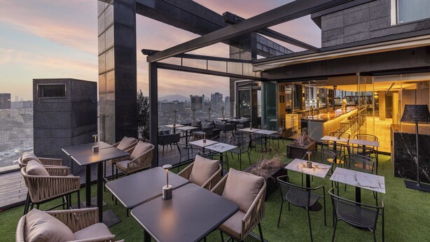 A rooftop bar with outdoor seating, a city view, and a modern architectural design. - AC Hotel by Marriott Seoul Gangnam (Seoul)