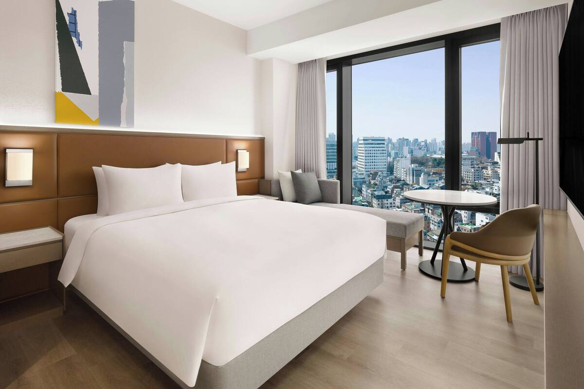 Une chambre d’hôtel moderne avec un grand lit, une table ronde et une vue sur la ville.