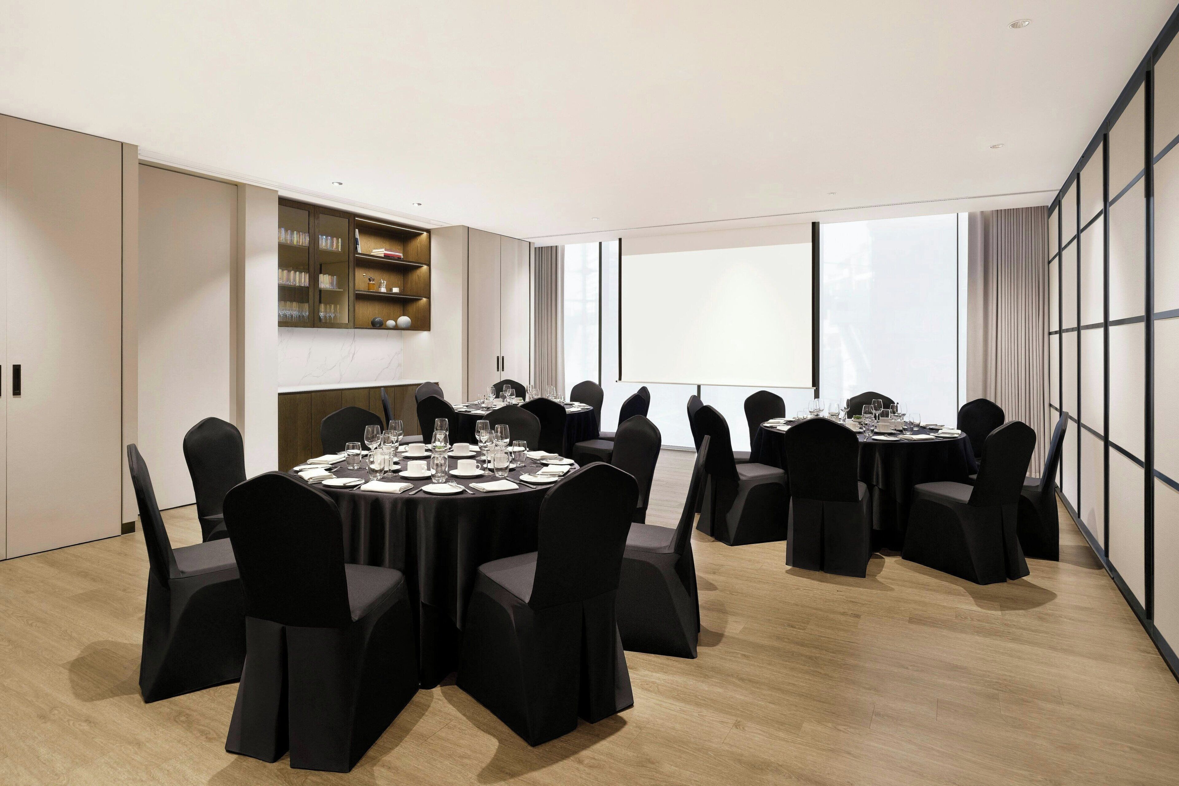 Una sala de conferencias moderna con mesas redondas, sillas negras y chimenea.