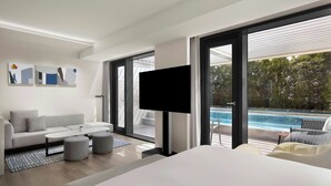 A modern hotel room with a large bed, a sofa, a TV, and a view of a swimming pool. - AC Hotel by Marriott Seoul Gangnam (Seoul)