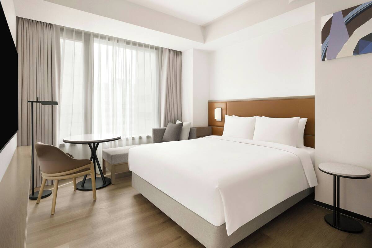 Une chambre d’hôtel avec un grand lit, une table ronde, une chaise et un téléviseur.