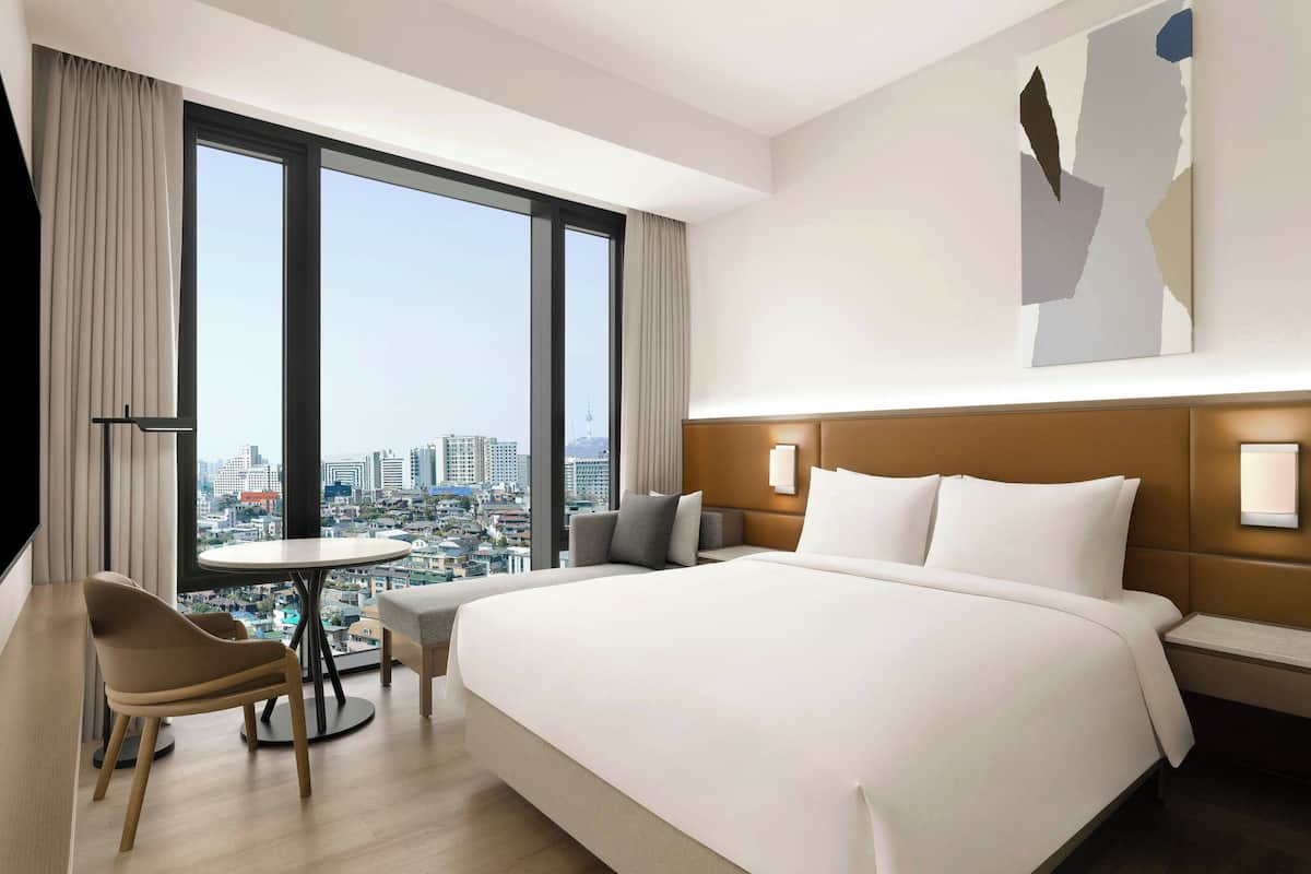 Une chambre d’hôtel moderne avec un grand lit, une table ronde et une vue sur la ville.