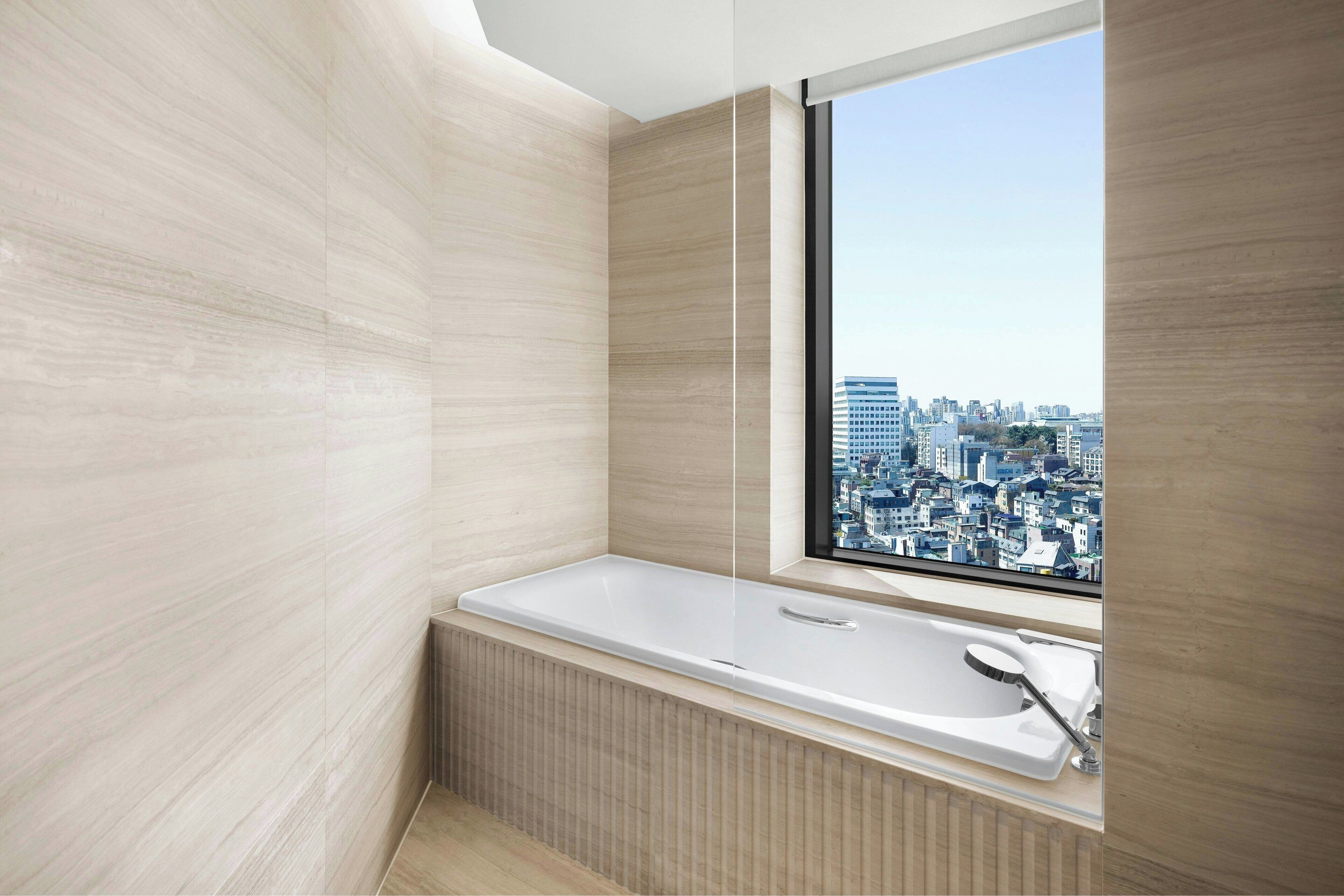 Une salle de bain moderne avec une grande baignoire, une fenêtre donnant sur la ville et un lambris en bois.