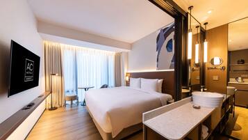 A modern hotel room with a large bed, a flat-screen TV, a bathroom with a sink and mirror, and a window with curtains.