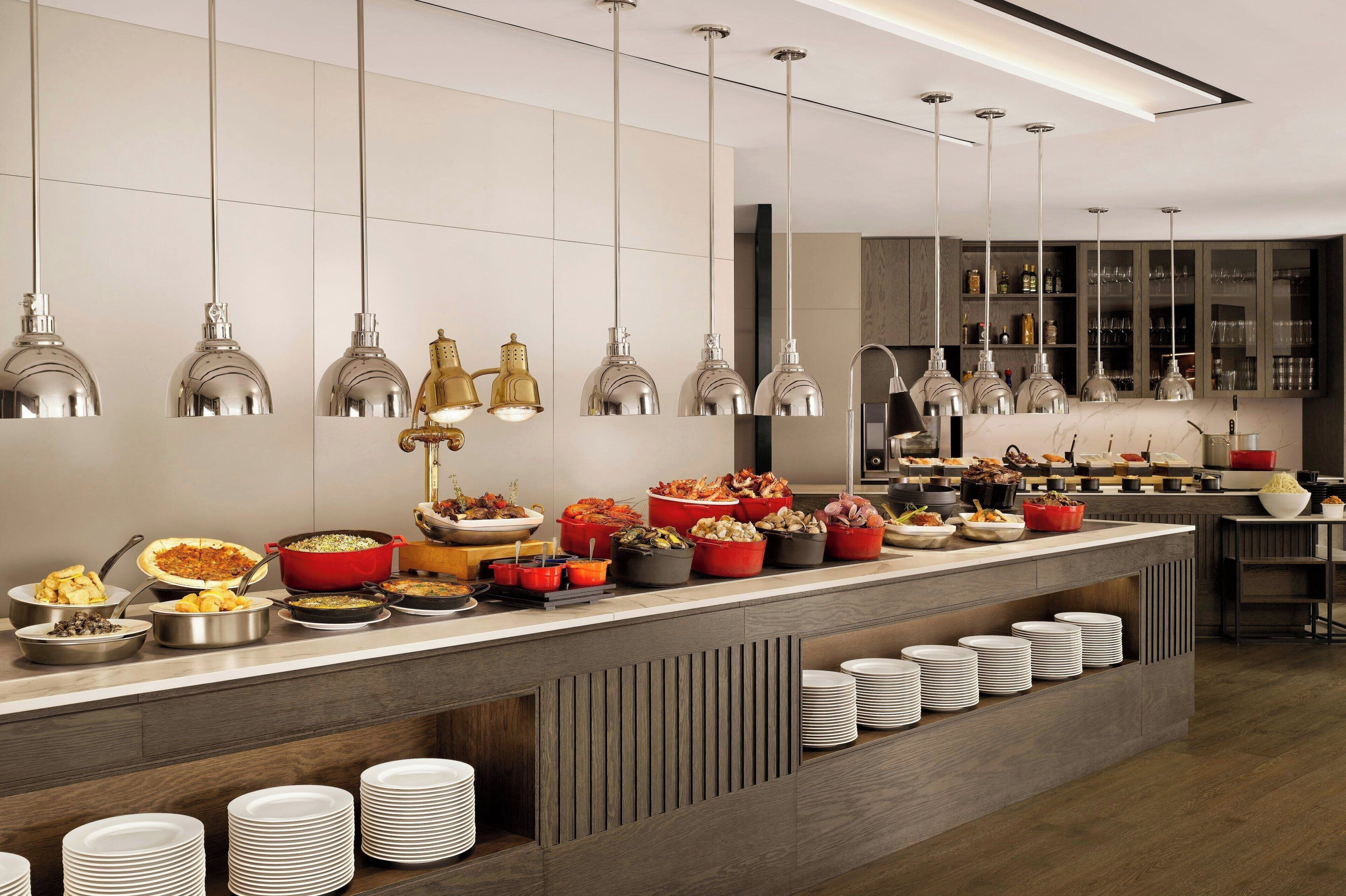 A buffet setup with various dishes and a modern kitchen area.