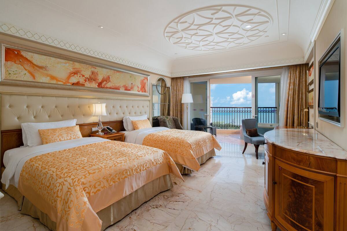 Une chambre d’hôtel avec deux lits, une grande œuvre d’art au mur, un balcon avec vue et un sol en marbre.