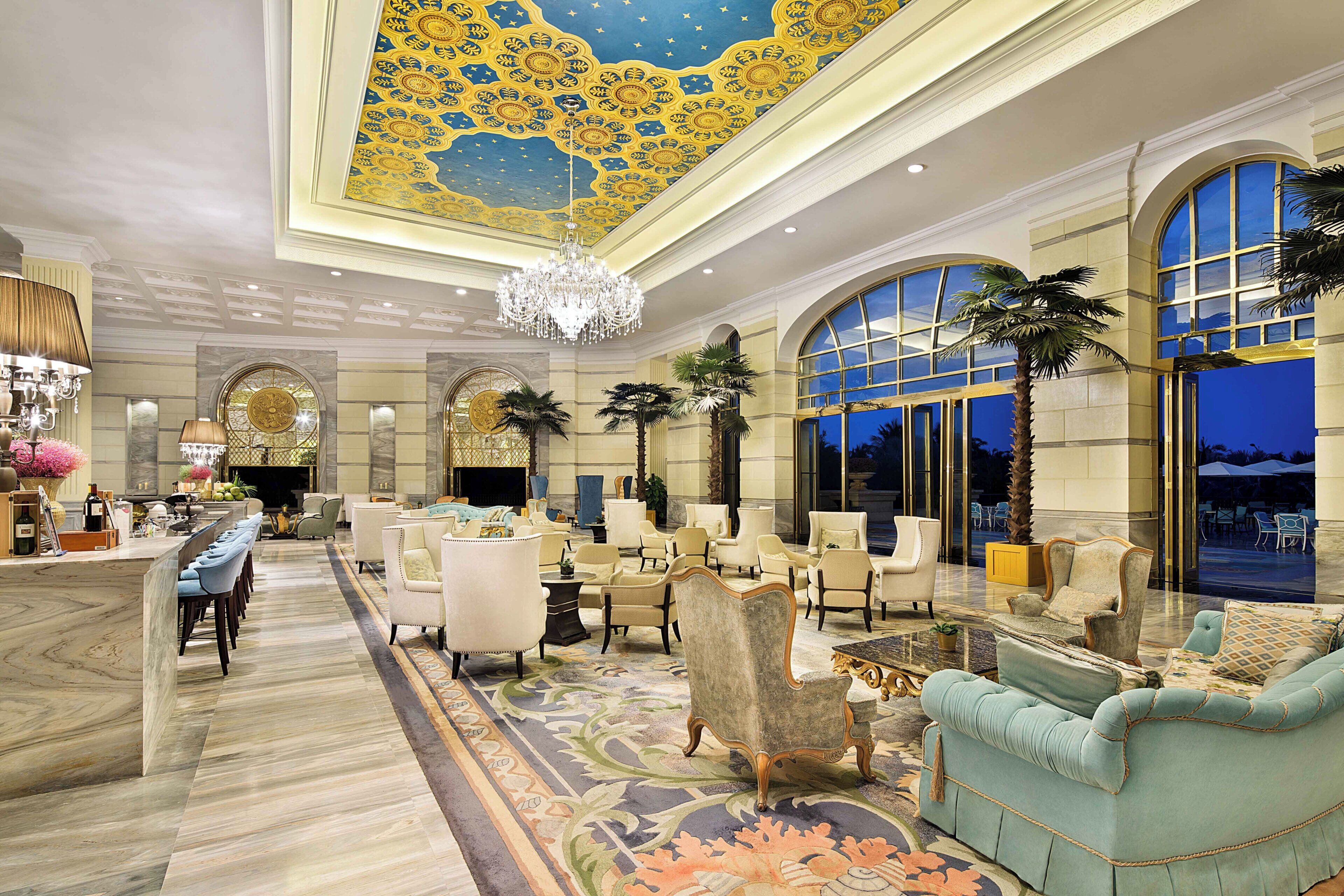 Eine geräumige Lobby mit hoher Decke, aufwendiger Deckenverzierungen und einem beeindruckenden Kronleuchter.