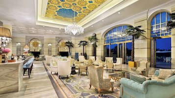 Eine geräumige Lobby mit hoher Decke, aufwendiger Deckenverzierungen und einem beeindruckenden Kronleuchter.