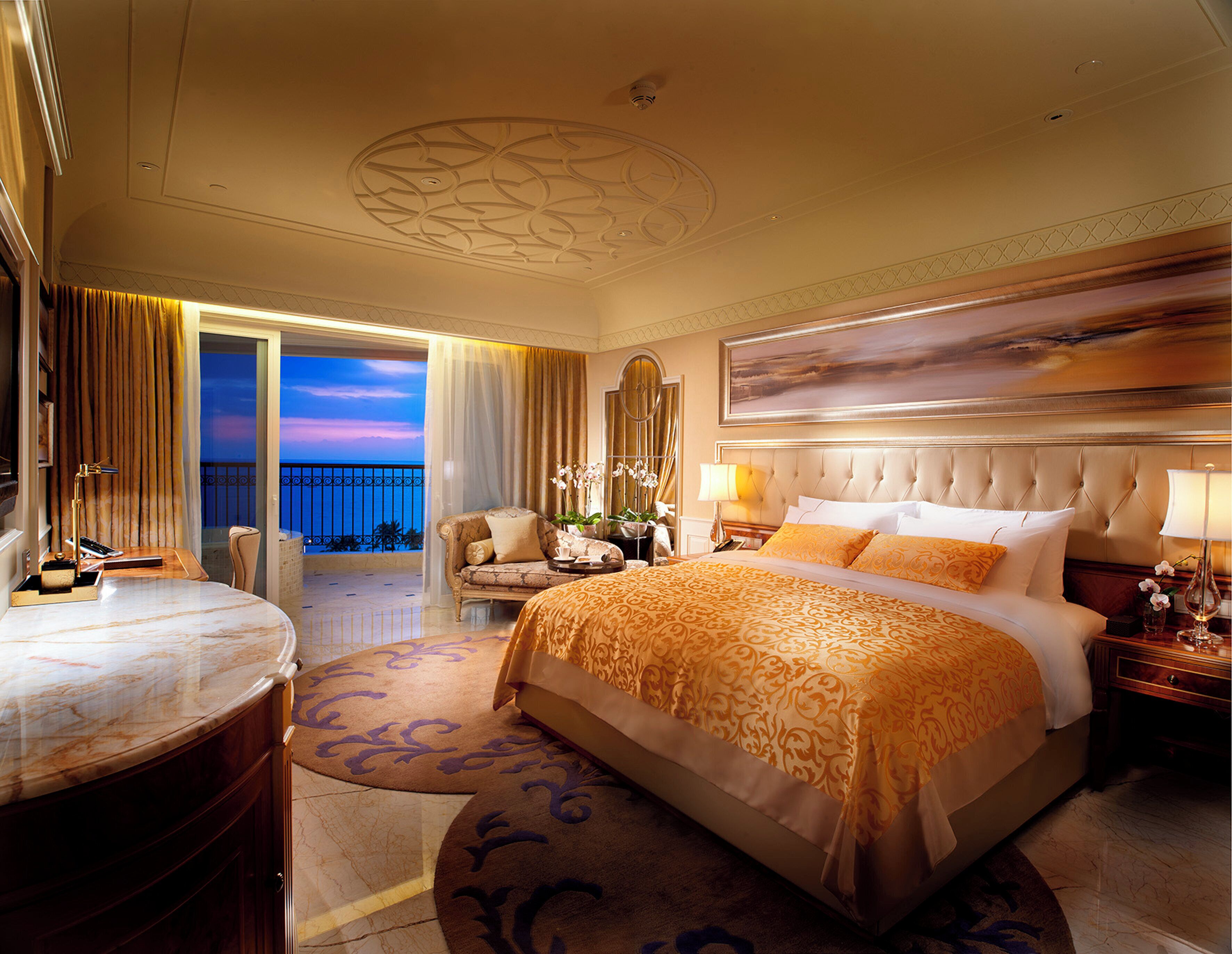 A hotel room with a large bed, a sitting area with a view, and a balcony.
