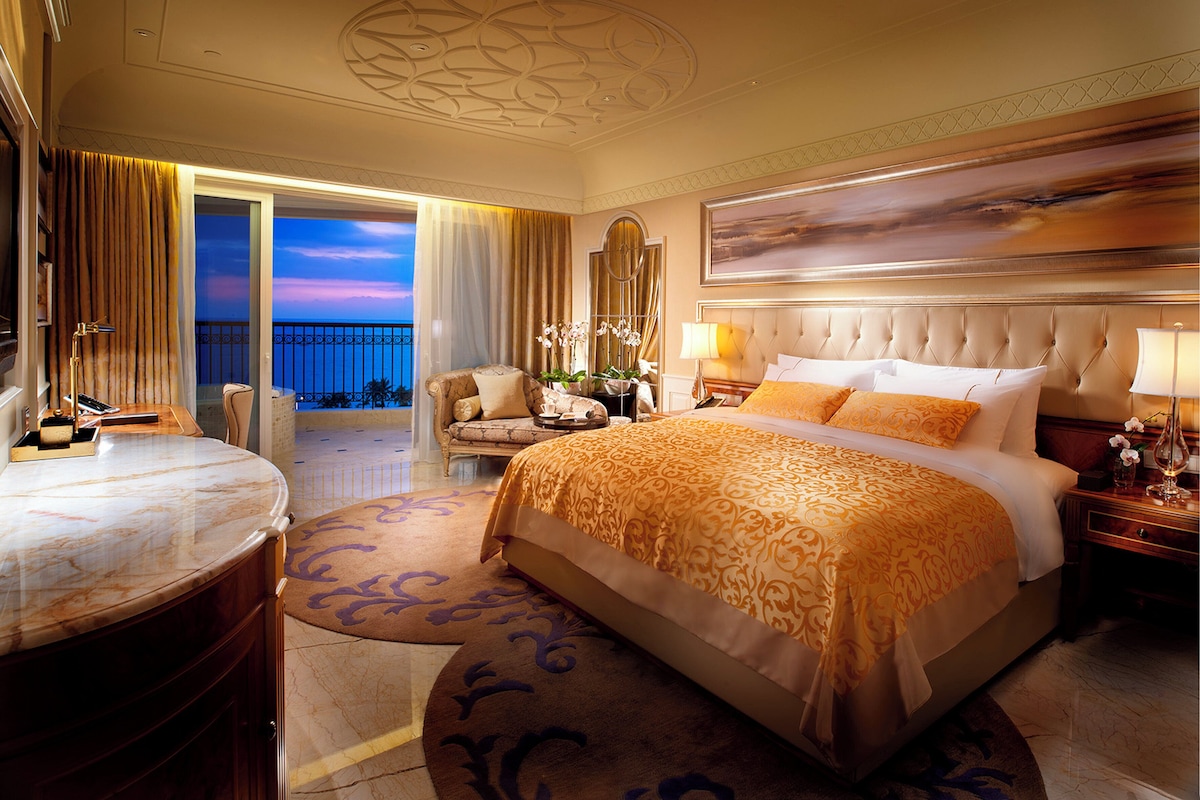 A hotel room with a large bed, a sitting area with a view, and a balcony.