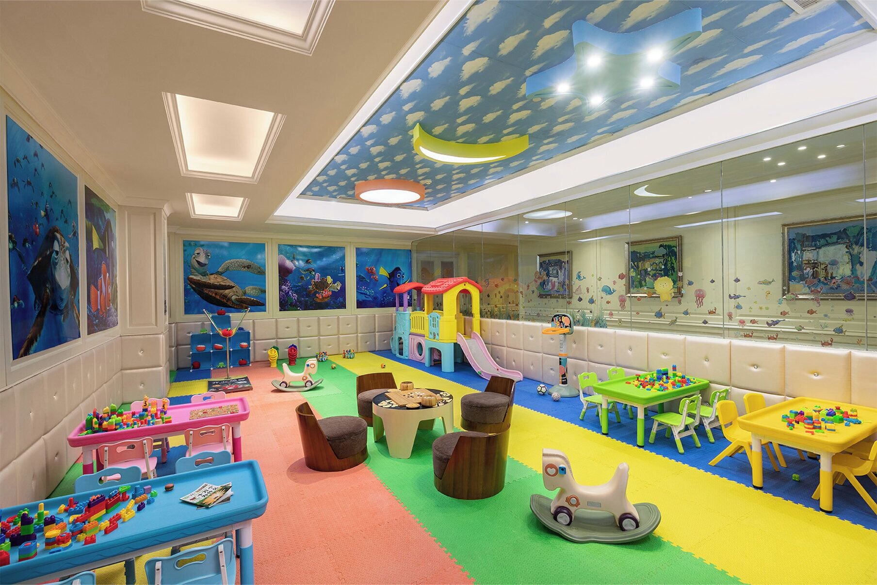 A children's playroom with a play area, seating, and artwork on the walls.