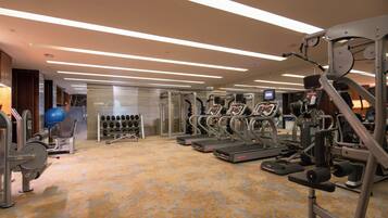 A gym with treadmills, weight machines, and a mirrored wall.