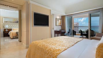 A hotel room with a large bed, a TV, a desk, and a balcony with a view of a building.