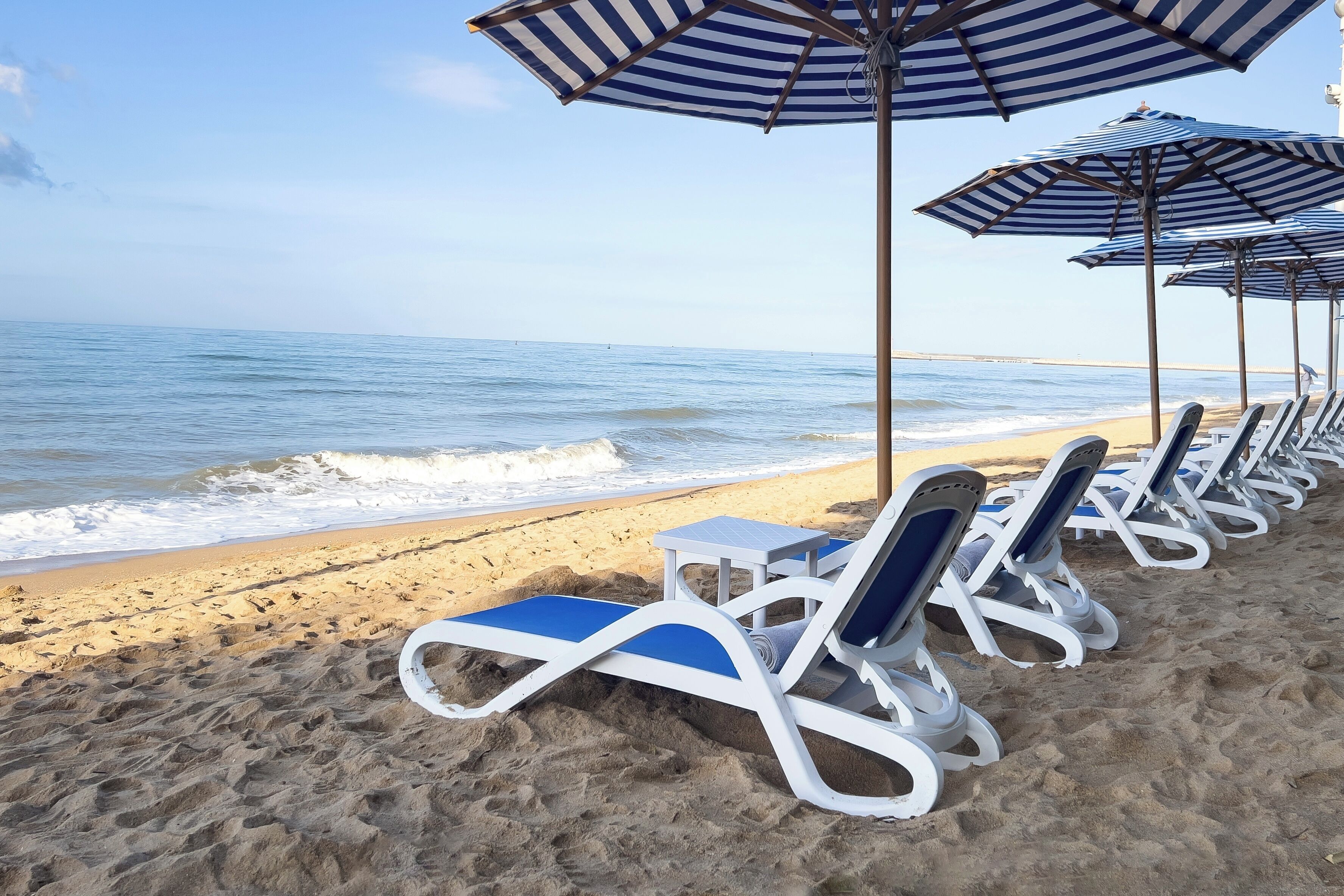 Una spiaggia con file di sdraio e ombrelloni a righe.