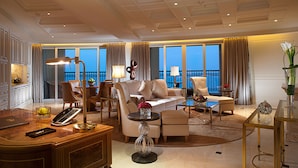 Un salon d’hôtel spacieux, comprenant un grand canapé, des fauteuils, une table basse et un bureau avec un téléphone.