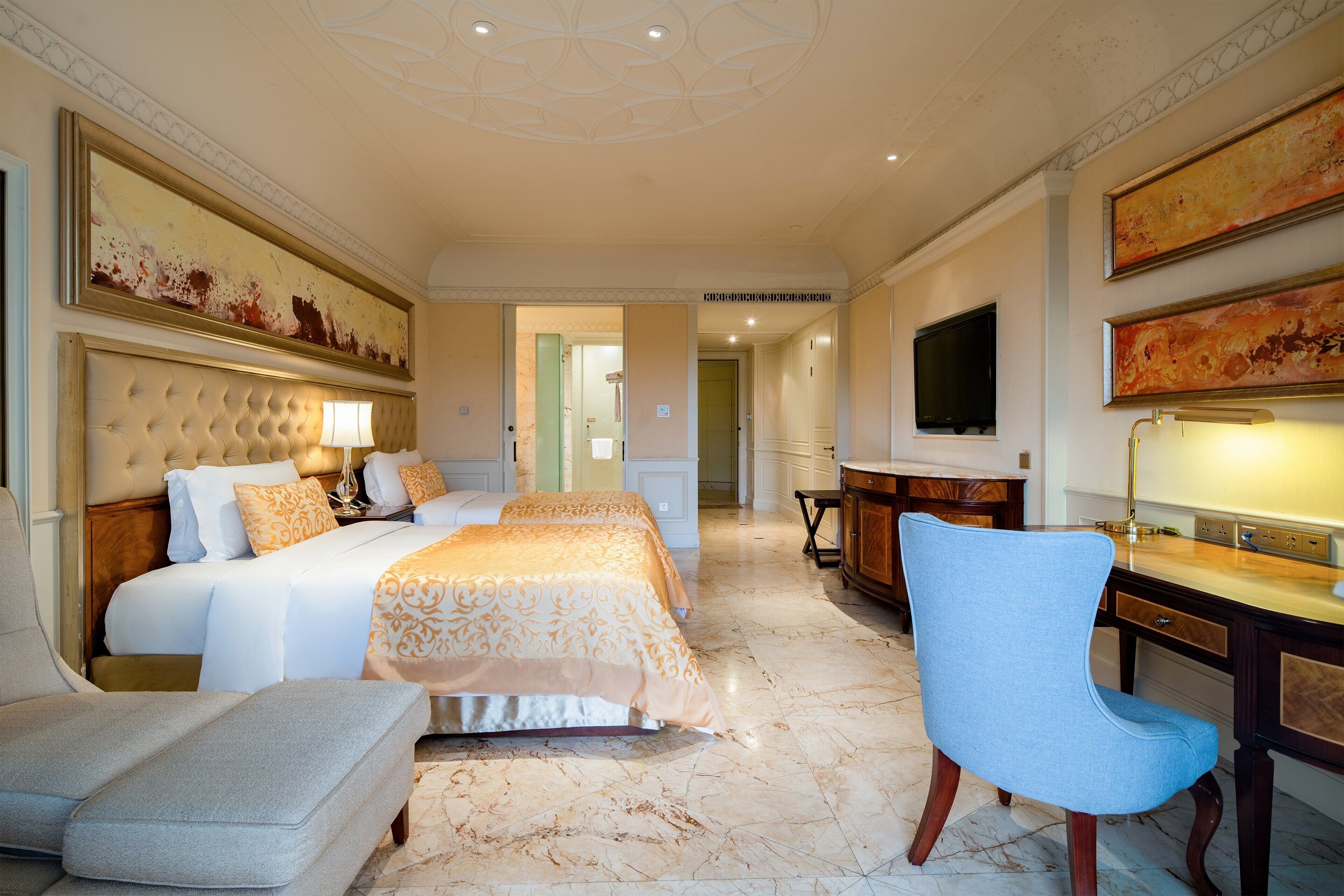 A hotel room with a large bed, a desk, a chair, and a TV.