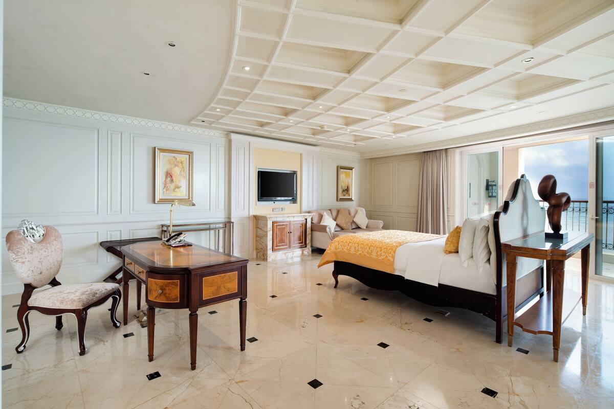 Une chambre d’hôtel spacieuse, dotée d’un grand lit, d’un bureau, d’une télévision et offrant une vue sur l’extérieur.