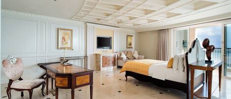 A spacious hotel room with a large bed, a desk, a television, and a view of the outdoors.