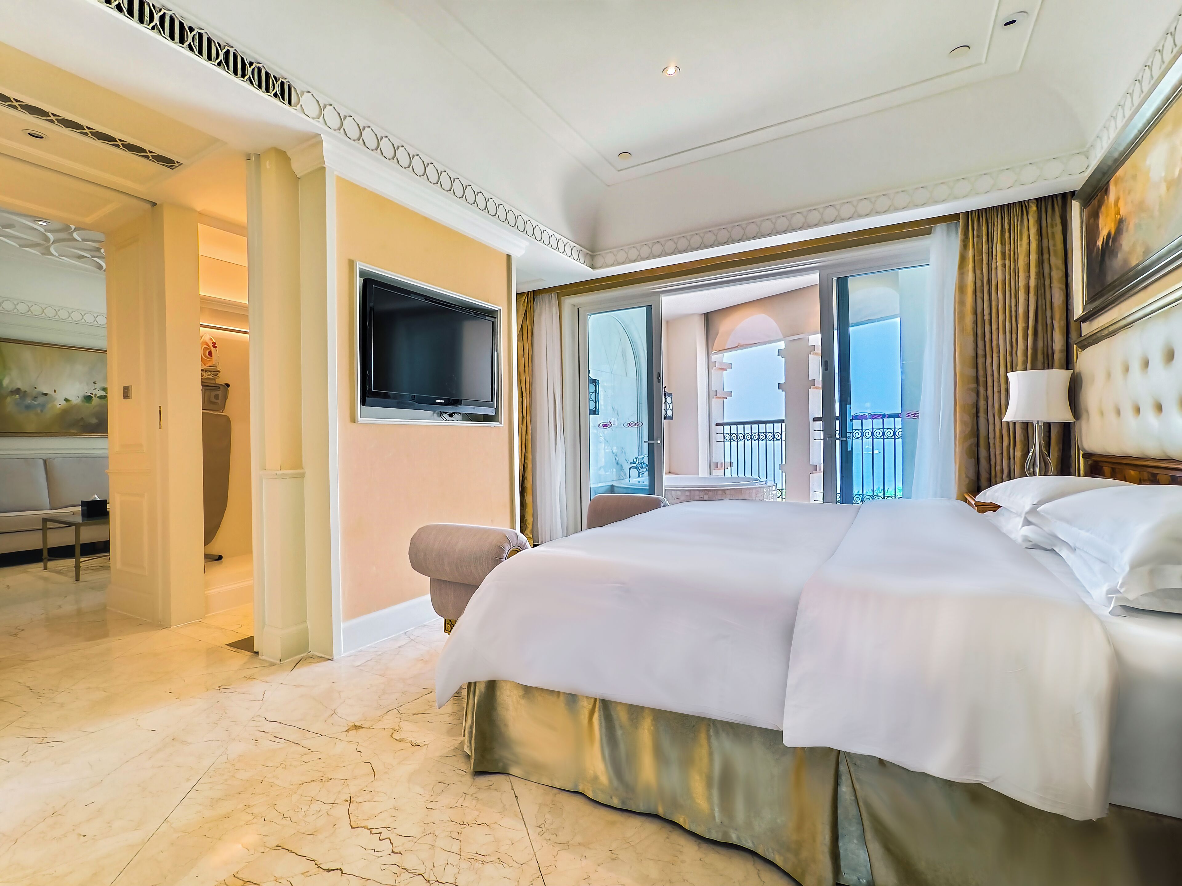 Ruime hotelkamer met een groot bed, een televisie en een balkon met uitzicht.