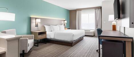 Habitación de hotel con cama, escritorio, silla y televisión de pantalla plana.