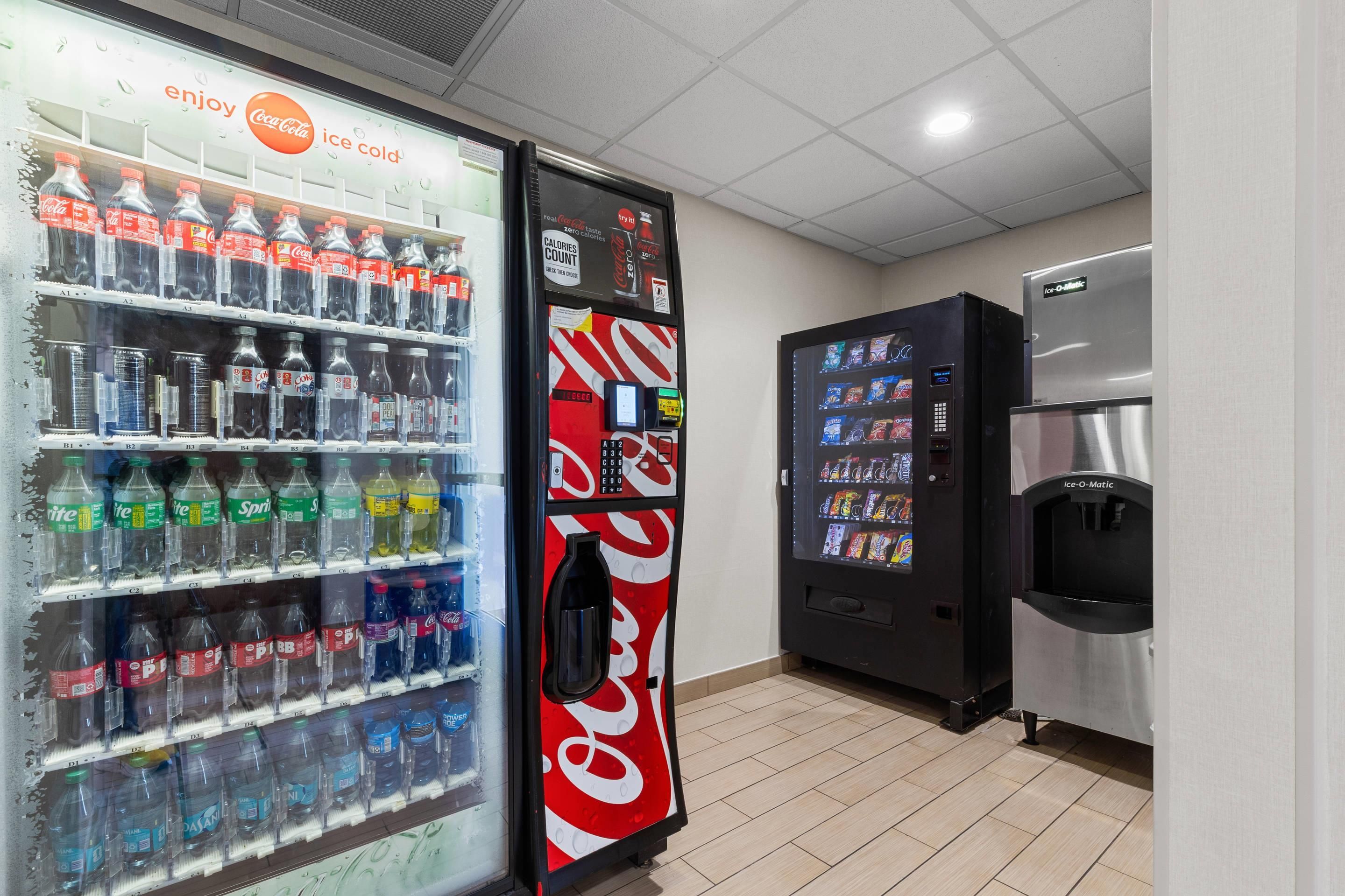 Un espace comprenant des distributeurs automatiques, avec un réfrigérateur pour les produits Coca-Cola, un réfrigérateur pour les produits Pepsi et un distributeur d’eau.