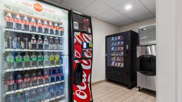 Un espace comprenant des distributeurs automatiques, avec un réfrigérateur pour les produits Coca-Cola, un réfrigérateur pour les produits Pepsi et un distributeur d’eau.